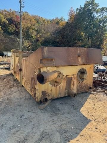 A large metal container is sitting in the dirt in a field.