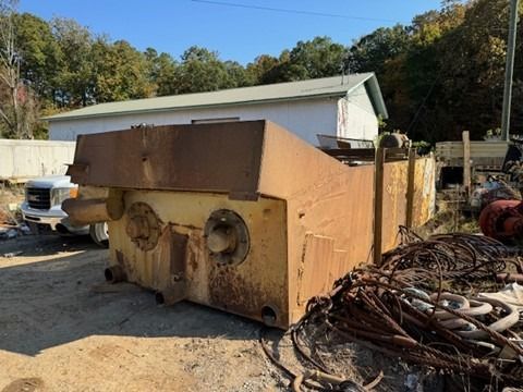 A large piece of rusty metal is sitting in the dirt in front of a building.