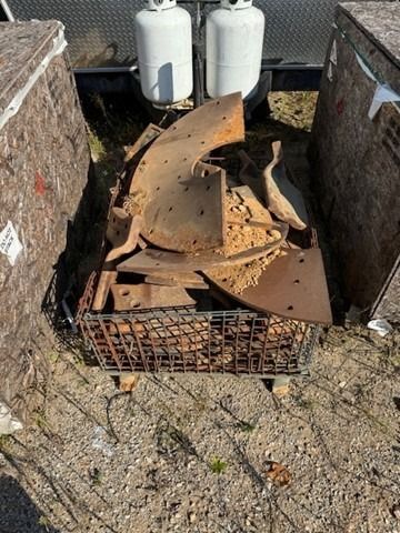 A pile of rusty metal is sitting in a cage on the ground.