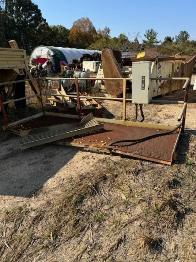 A lot of machinery is sitting in the dirt and one of the boxes has the letter b on it