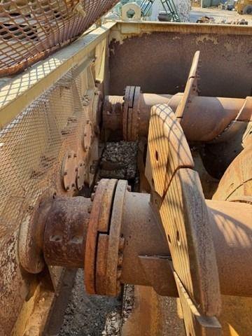 A close up of a rusty metal pipe with a fence in the background.