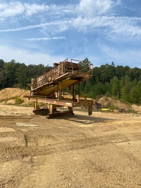 A large machine is sitting in the middle of a dirt field.