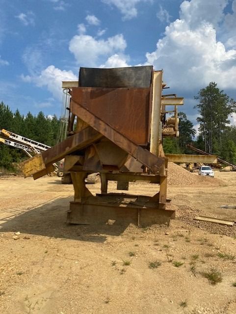 A large machine is sitting in the middle of a dirt field.