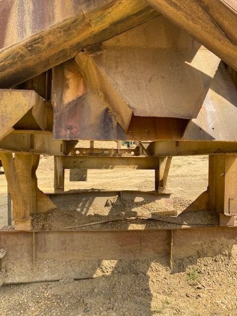 A large metal structure is sitting on top of a dirt field.