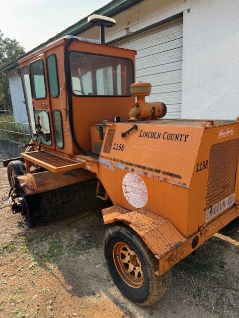 A lincoln county tractor is parked in front of a garage