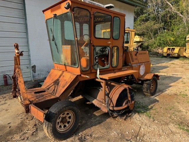 An old rusty tractor is parked in front of a building