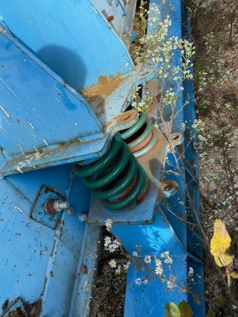 A green spring is sitting on top of a blue object