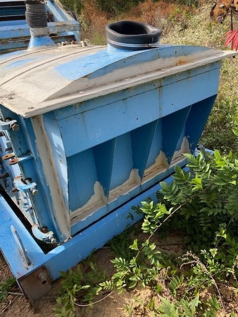 A blue machine is sitting on the ground in a field.
