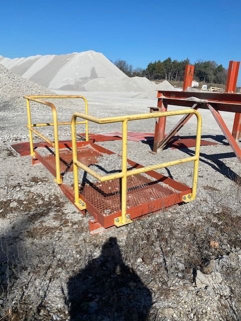 A yellow railing sits in the dirt near a pile of gravel