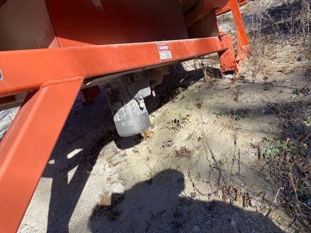 A large orange container is sitting on top of a dirt field.