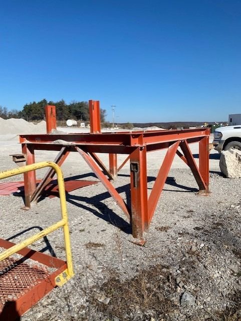 A metal structure with a yellow railing is sitting in the dirt.