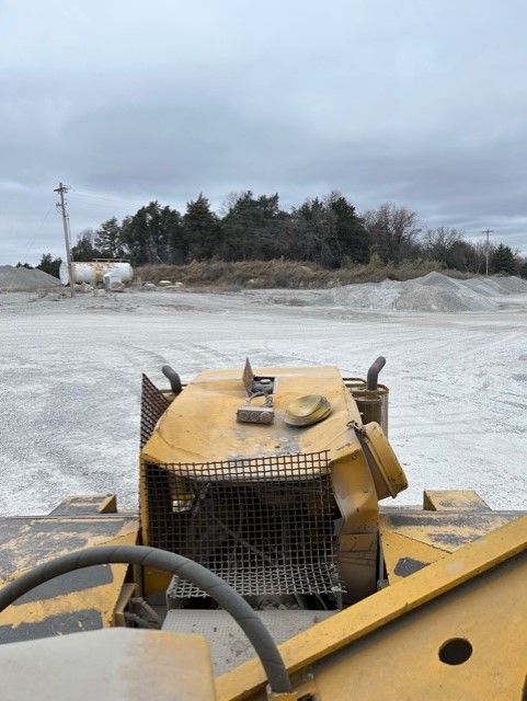 A yellow bulldozer is parked in a dirt field.