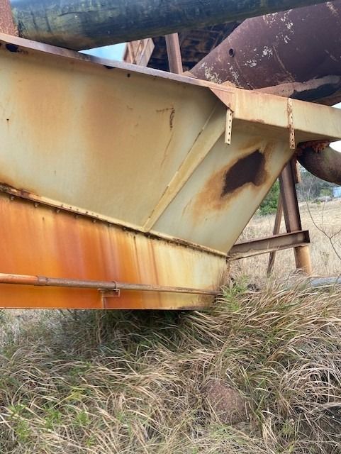 A rusty metal structure is sitting in the middle of a field.