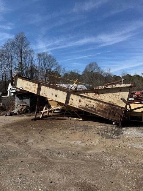 A large metal structure is sitting on top of a dirt field.