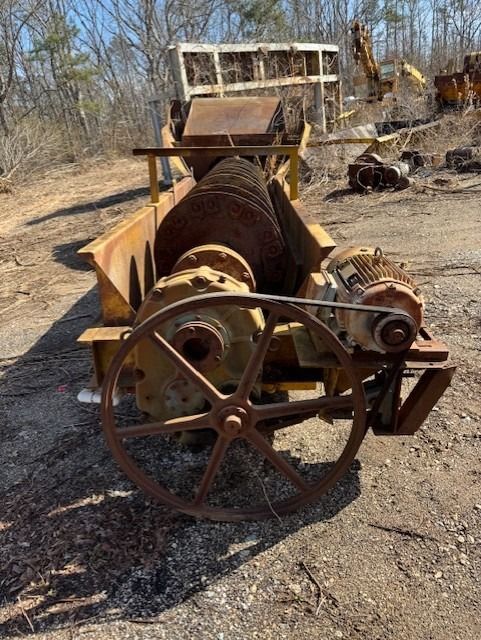 An old rusty machine is sitting in the dirt in a field.