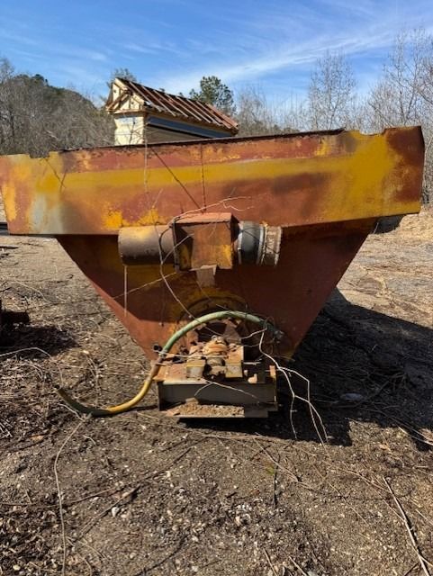 A large rusty metal object is sitting on top of a dirt field.