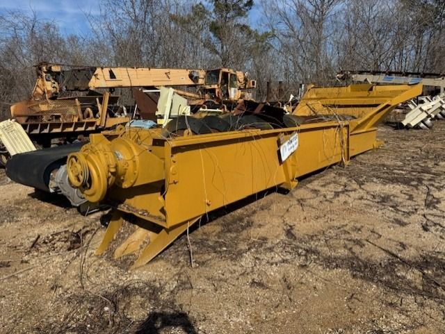 A large yellow machine is sitting in the dirt in a field.