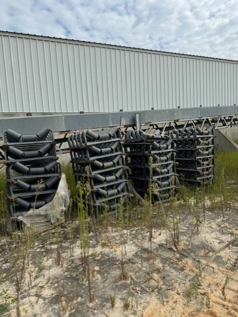 A bunch of tires are stacked on top of each other in a field in front of a building.
