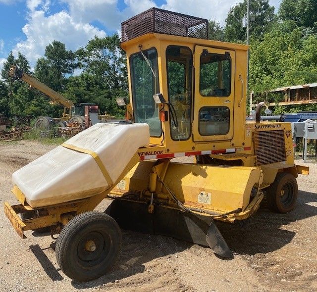 A yellow tractor is parked in a dirt lot