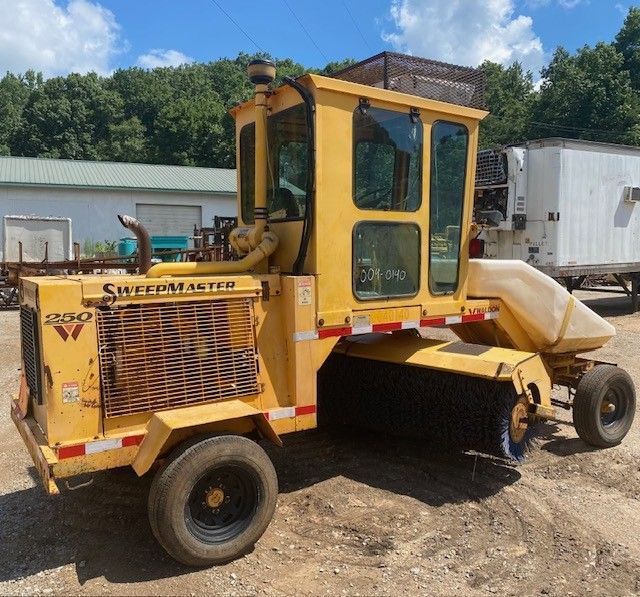 A yellow super atlantic tractor is parked in a dirt lot