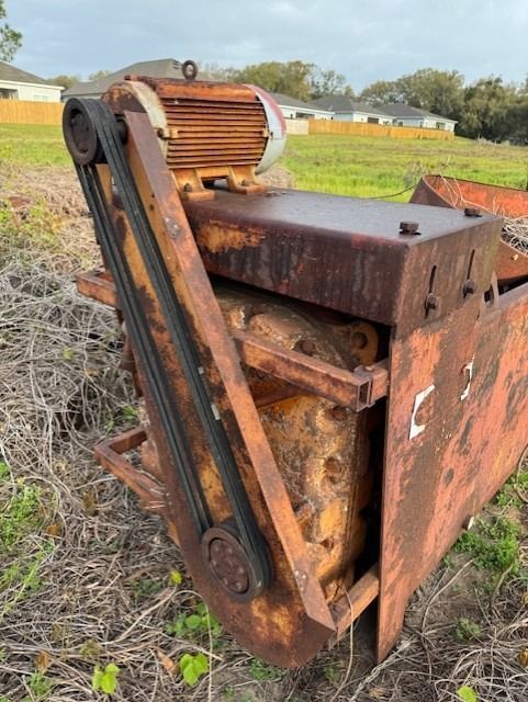 A rusty machine is sitting in the middle of a field.