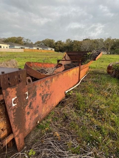 A rusty boat is sitting in the middle of a grassy field.