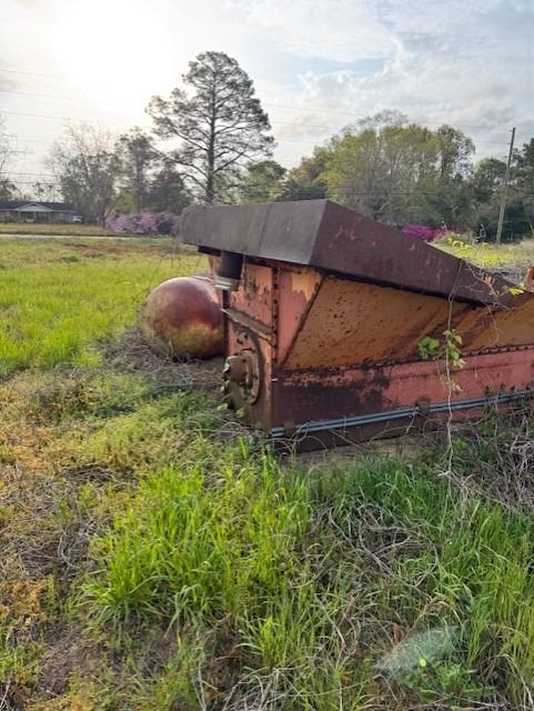 An old rusty tractor is sitting in the middle of a grassy field.