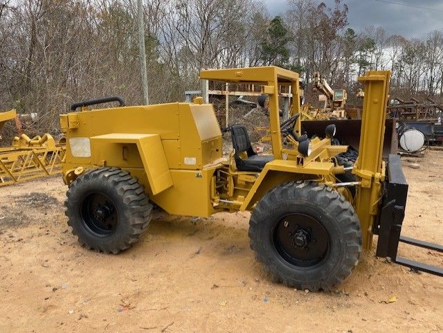 A yellow forklift is parked in a dirt lot.