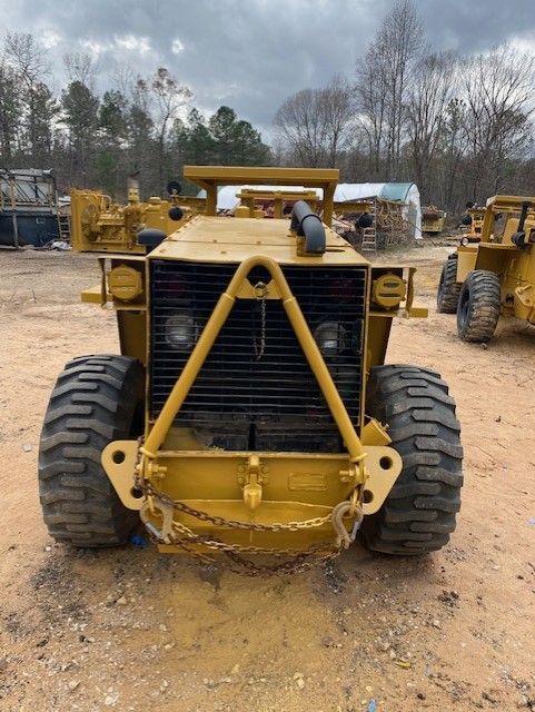 A yellow tractor is parked in a dirt field