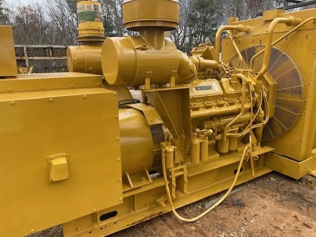 A yellow generator with a fan attached to it is sitting in the dirt.