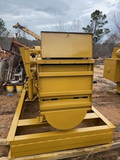 A large yellow machine is sitting in the dirt