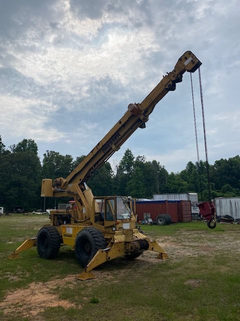 A large yellow crane is parked in a grassy field
