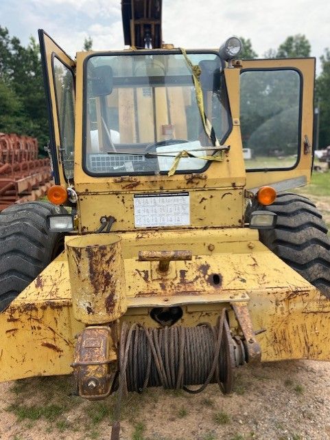 A yellow tractor is parked in a field with its doors open