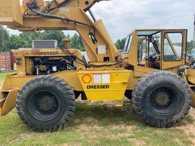 A yellow dresser tractor is parked in a grassy field