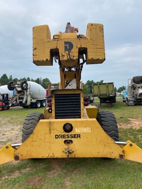 A yellow dresser tractor is parked in a grassy field