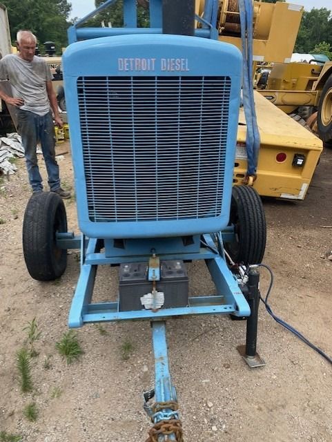 A man standing next to a blue detroit diesel tractor