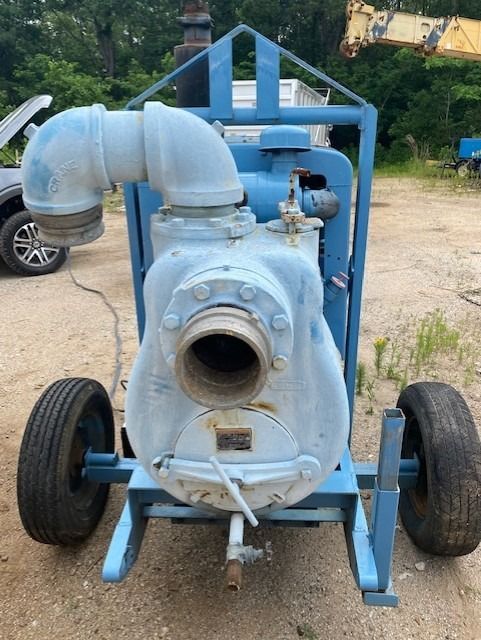 A blue water pump with wheels is sitting in the dirt
