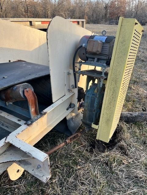 A machine is sitting in the grass with a motor attached to it.