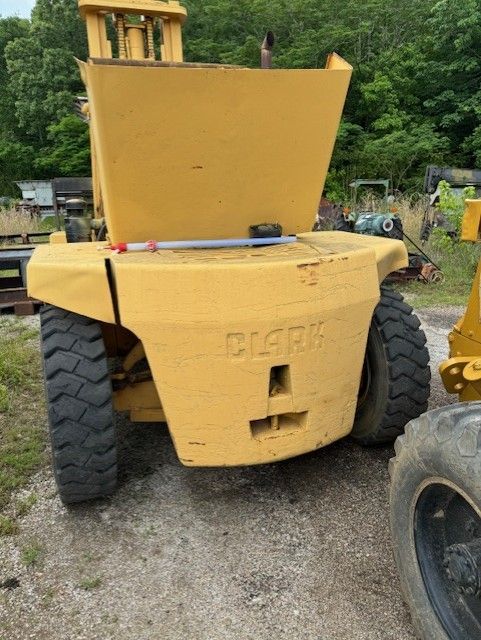 A yellow clark dump truck is parked in a gravel lot