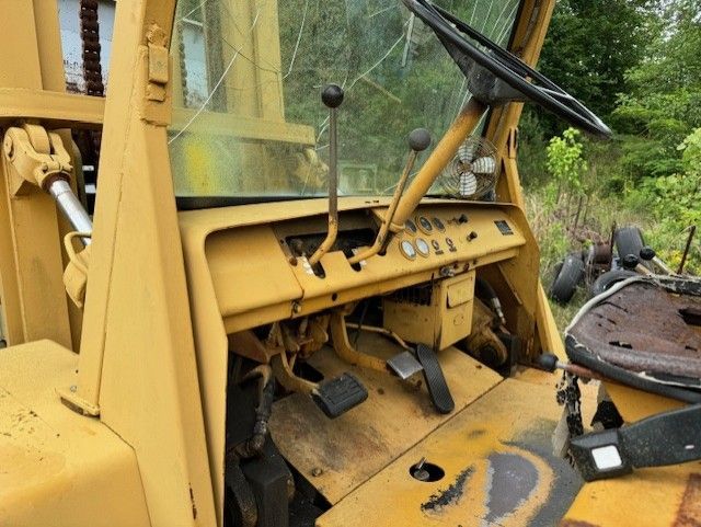 The inside of an old yellow forklift with a steering wheel