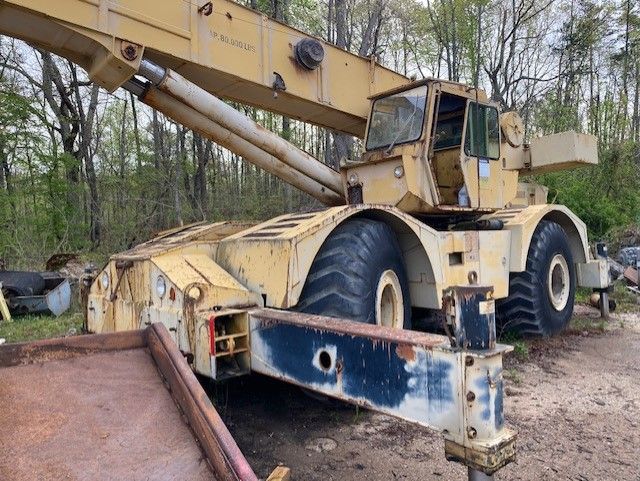 A large yellow crane is parked in a dirt field.