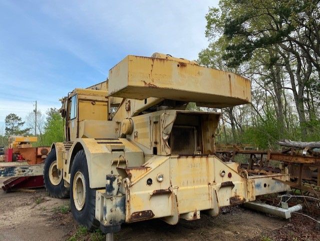 A large yellow truck is parked in a dirt lot.