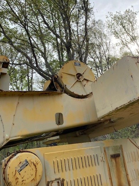 A close up of a yellow and white machine with trees in the background.