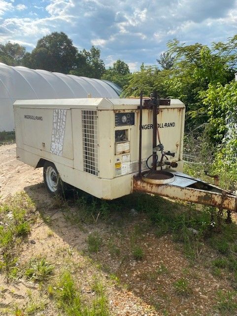 A trailer with a compressor on it is parked in a field.