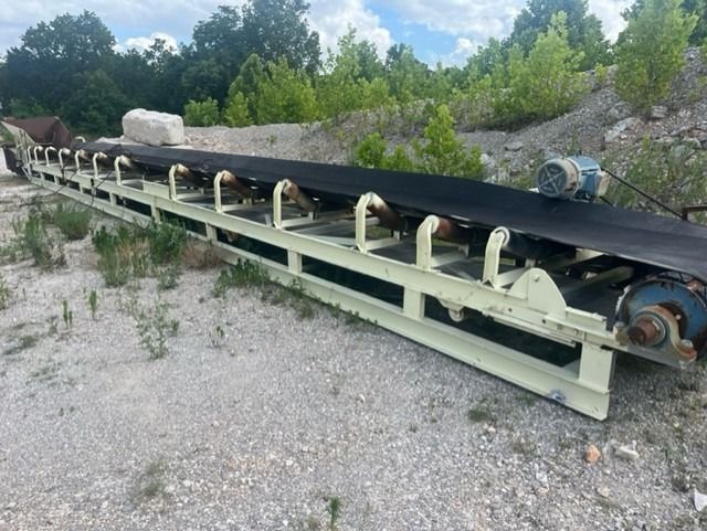 A conveyor belt is sitting on top of a dirt field.