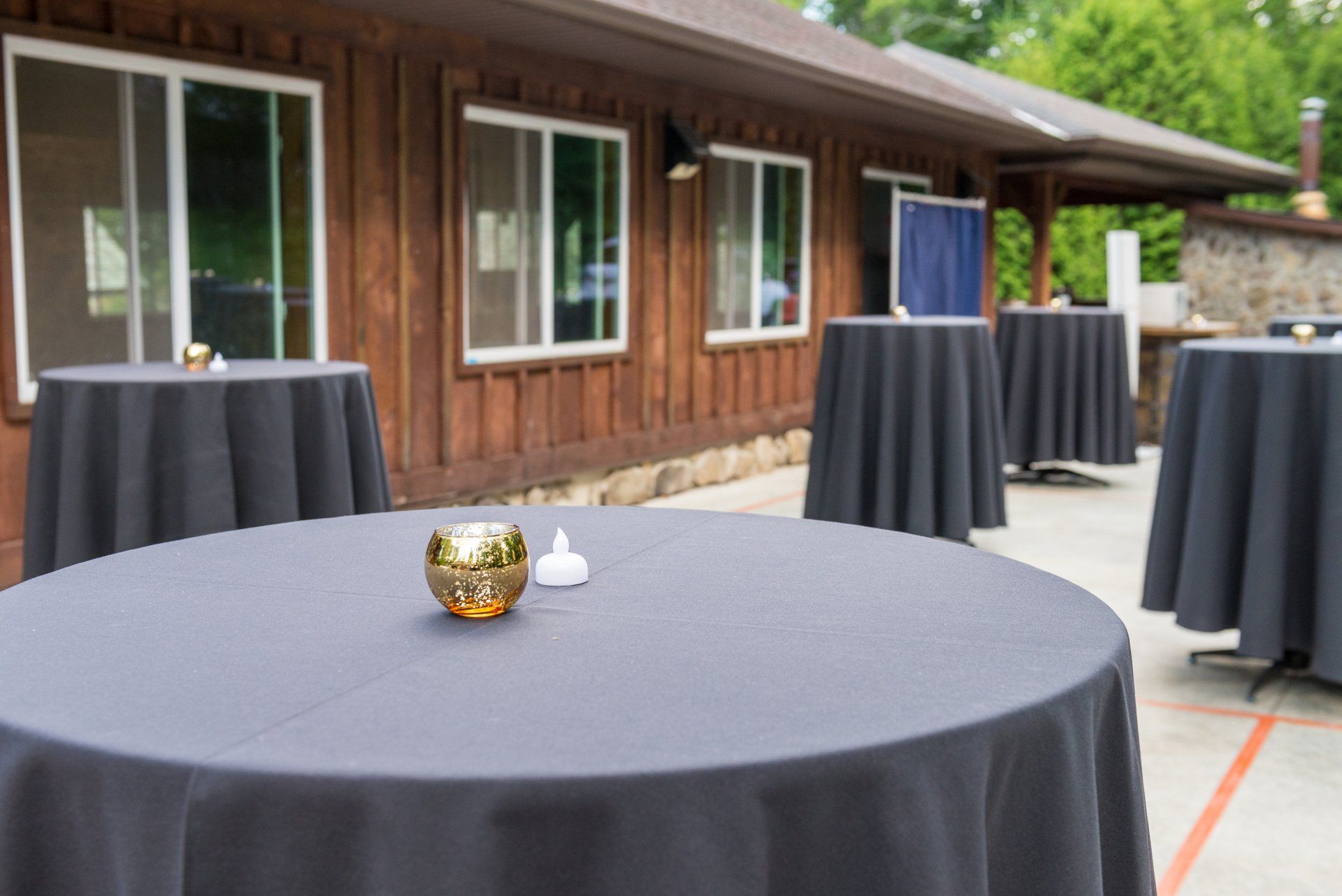 A table with a candle on it in front of a wooden building.