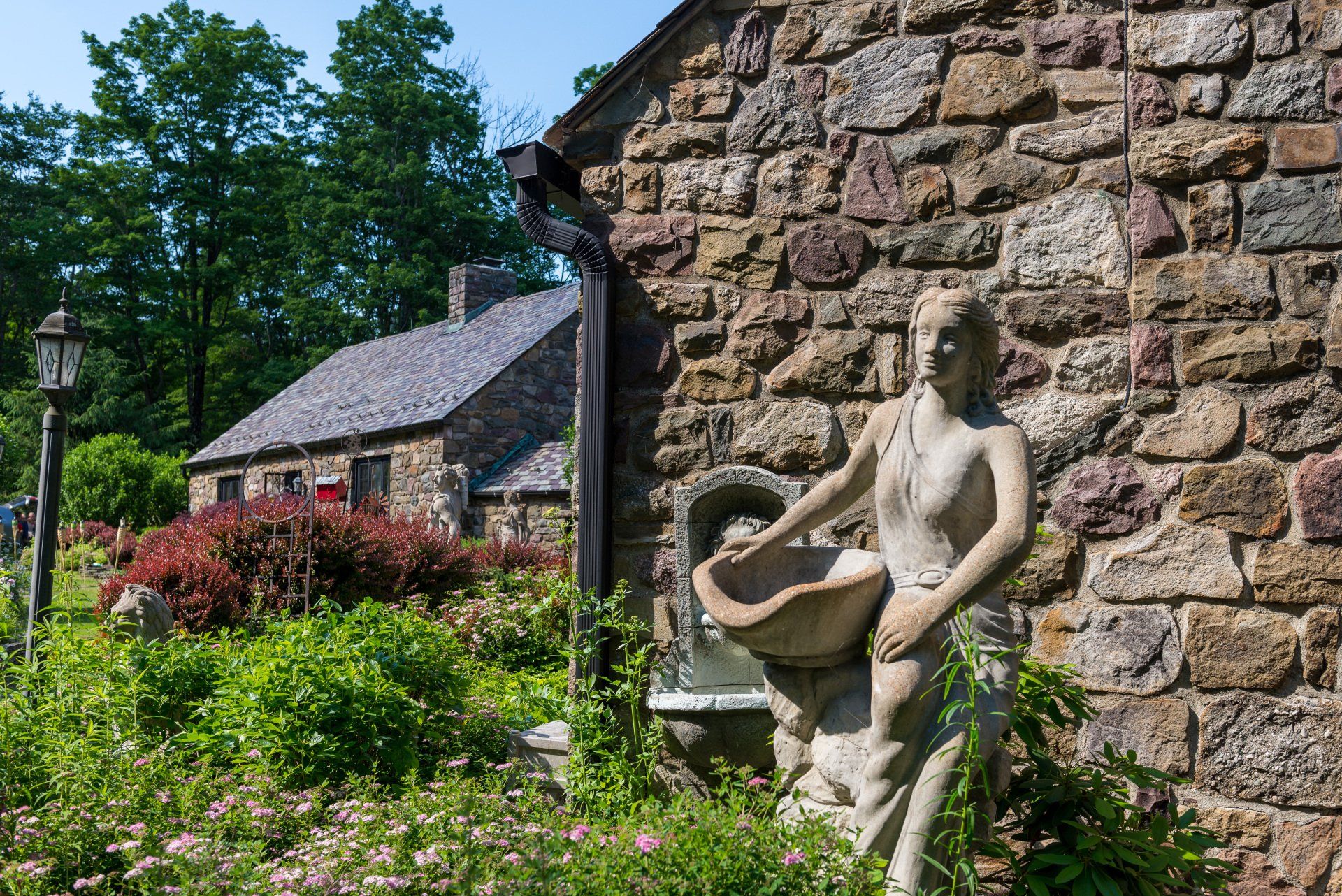 A statue of a woman holding a bowl in front of a stone wall.