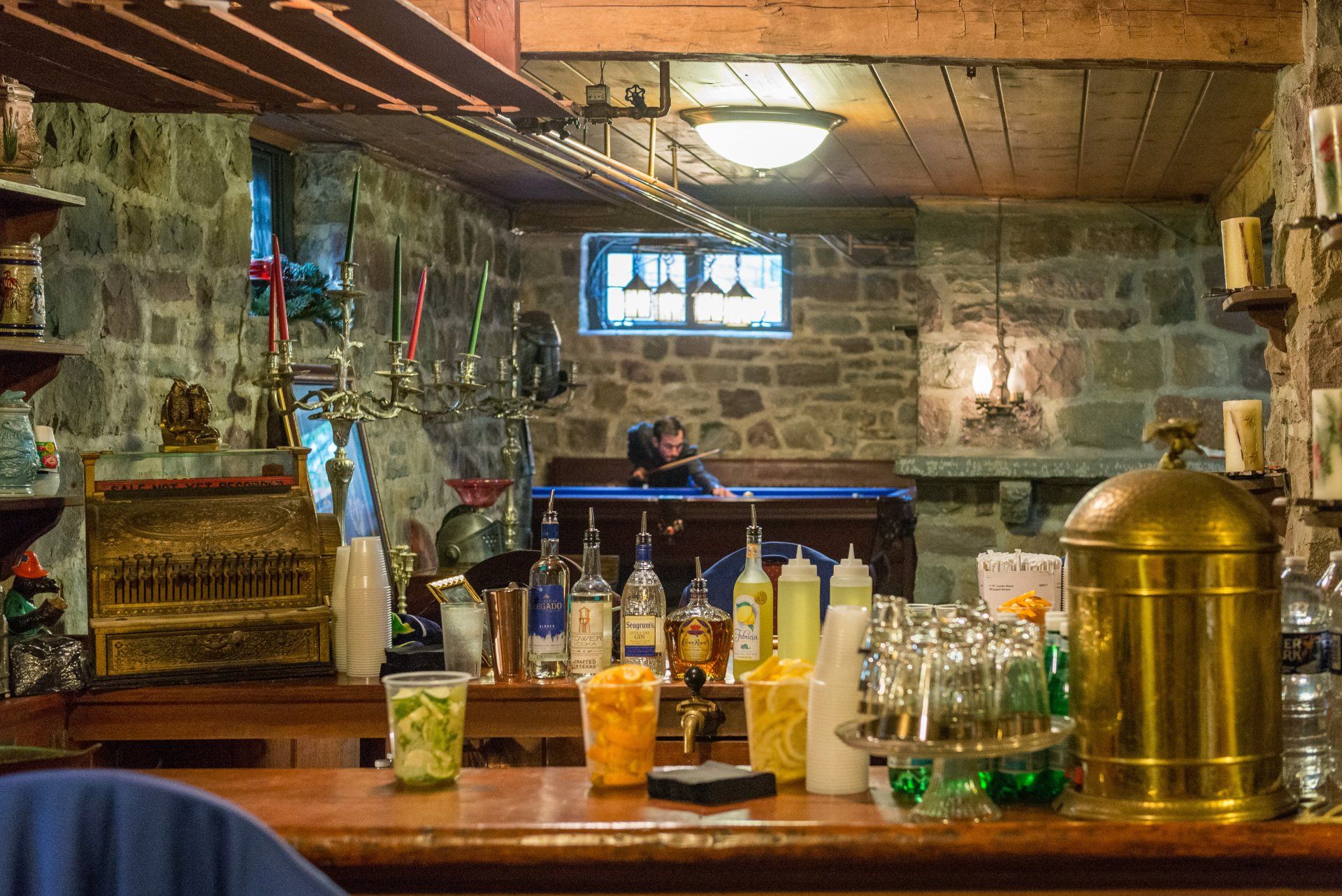 A man is sitting at a pool table in a basement bar.