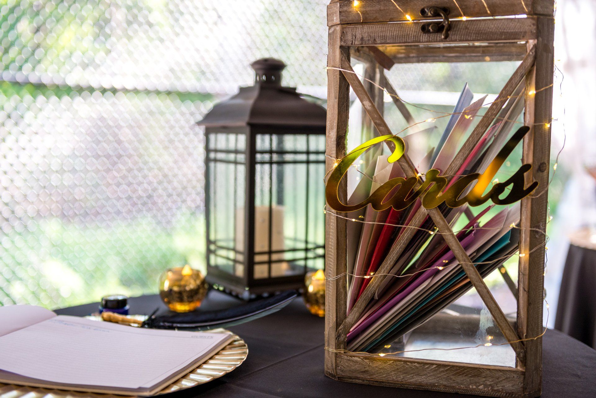 A wooden lantern filled with pencils is sitting on a table next to a lantern.