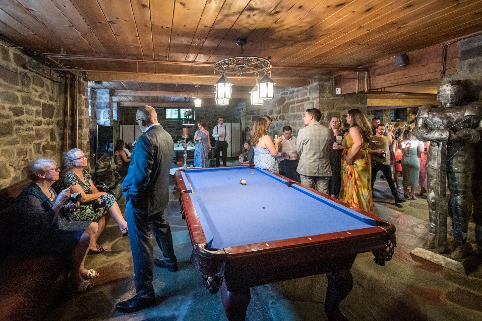 A group of people are standing around a pool table.